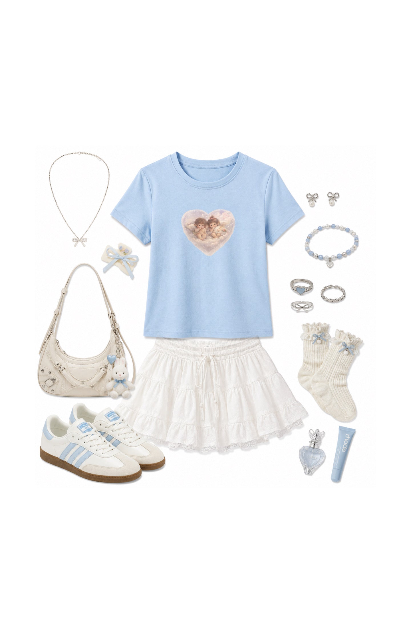A flat-lay outfit arrangement featuring a light blue short-sleeve t-shirt with a heart graphic, a white ruffled skirt, white sneakers, a cream shoulder bag, white socks, jewelry, and a small tube of cream-colored product, all arranged on a plain white background.